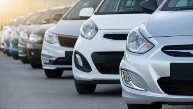 Row of used hatchbacks parked nose-on at a dealership at sunset