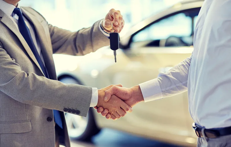 Buyer inspecting a used car before handing over payment