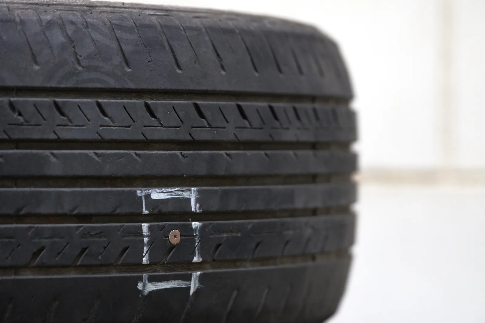 Nail head embedded in the tread of a worn car tyre