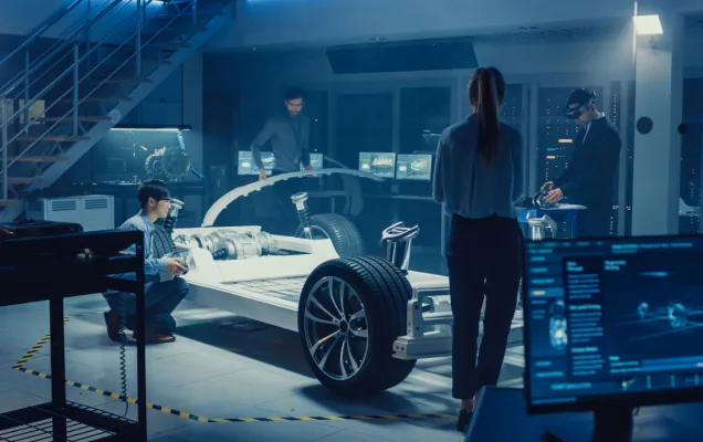 Engineers examining an electric car's battery skateboard chassis in a design lab