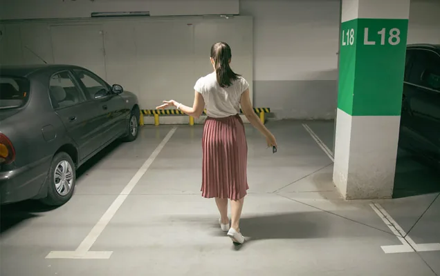 Woman walking through an underground car park with her car key in hand