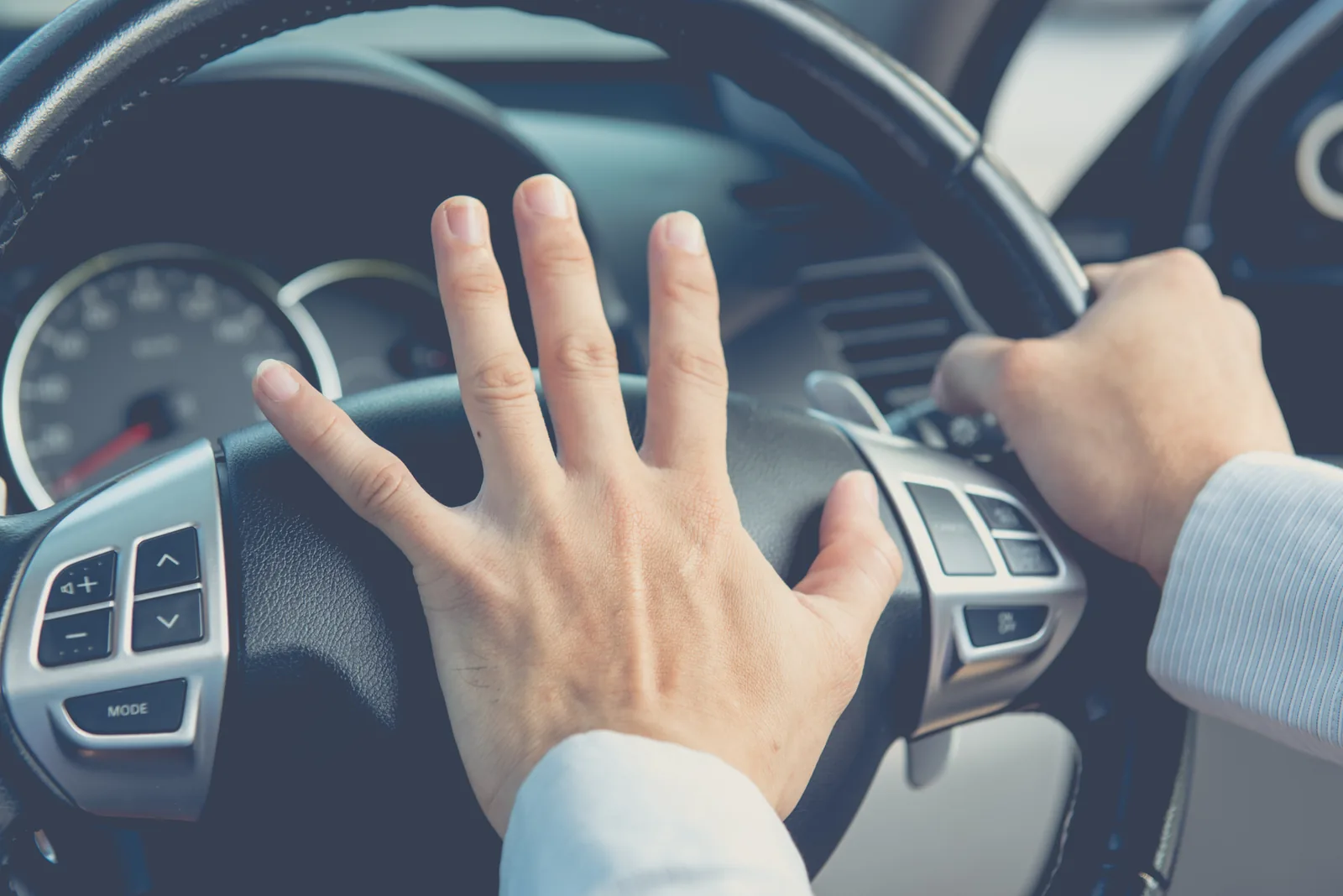 Driver pressing the horn in the centre of the steering wheel