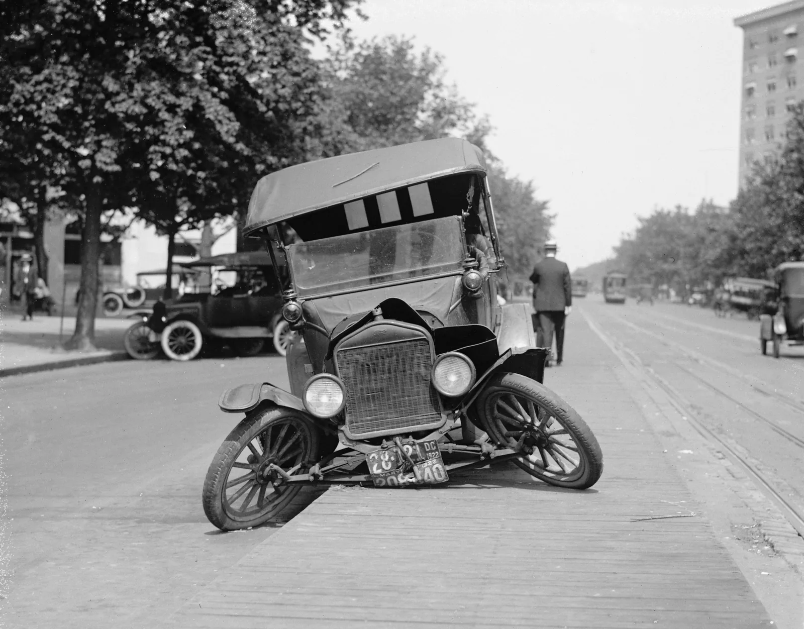 Vintage photograph of a wrecked early motor car sitting on a city street
