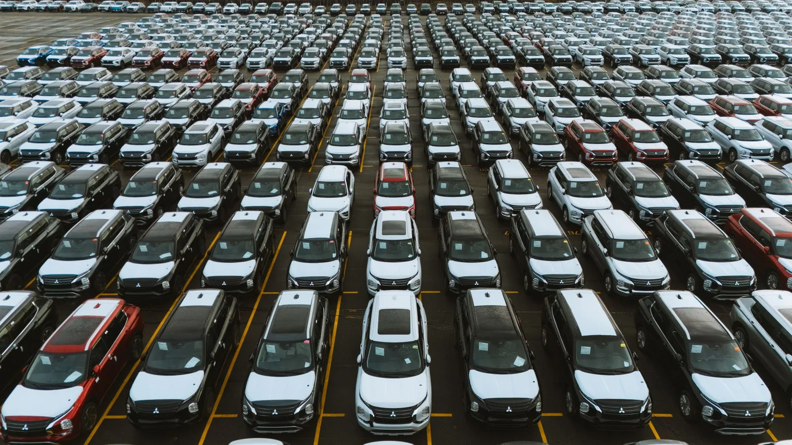 Aerial view of hundreds of used cars lined up in rows at a vehicle storage lot
