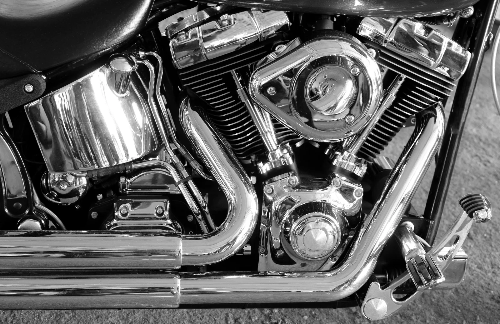 Black and white close-up of a chrome V-twin engine's cylinders and exhaust pipes