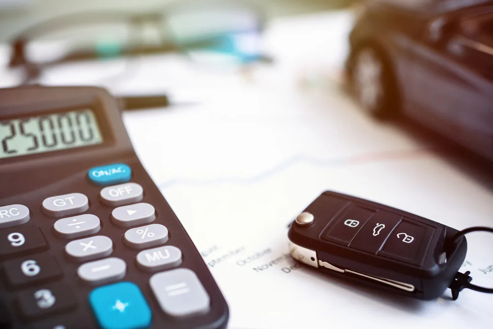 Calculator showing 25,000 next to a car key resting on a price chart