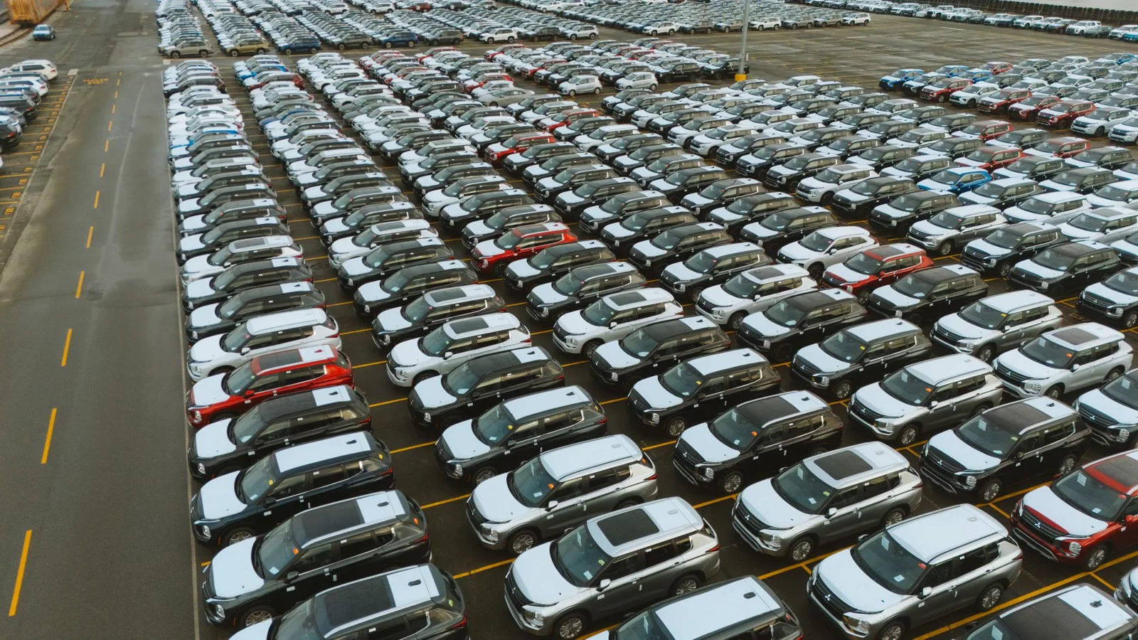 Aerial view of a distribution yard packed with rows of brand-new cars waiting to be delivered to dealers