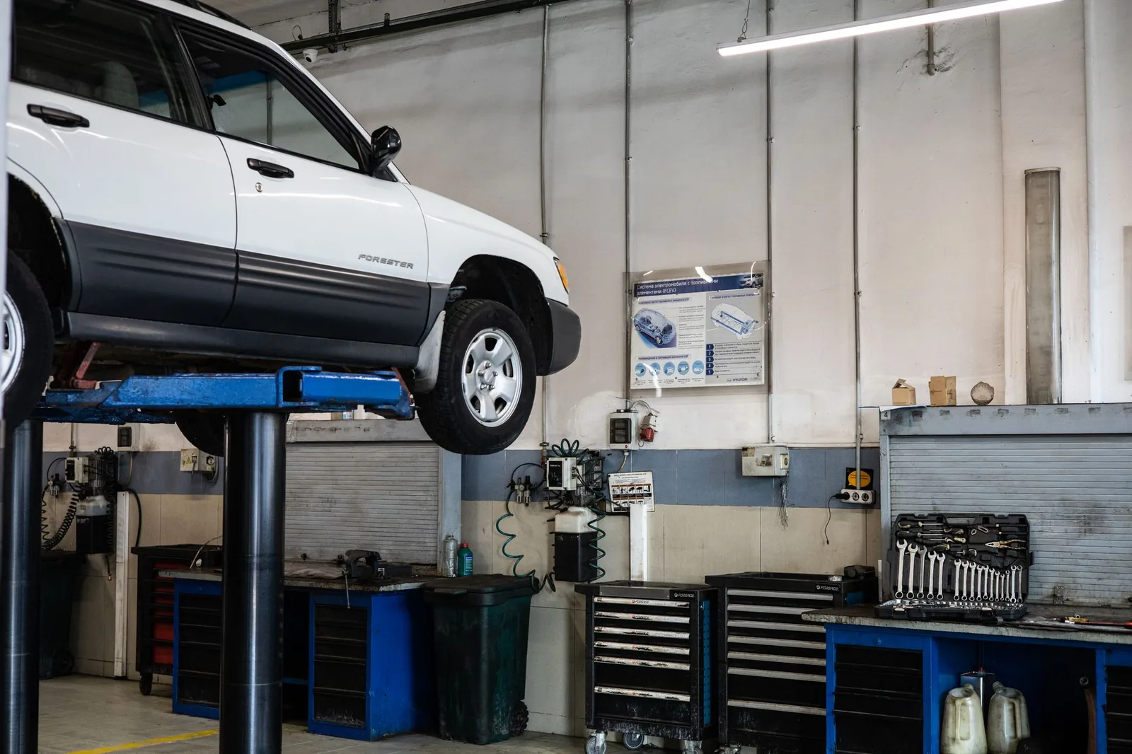 A used wagon raised on a two-post hoist in a workshop, ready for an underbody inspection.