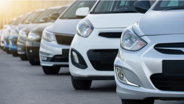 Row of used hatchbacks parked nose-on at a dealership at sunset
