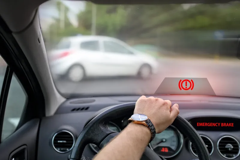 Red brake warning projected onto a car's dash as a vehicle crosses ahead