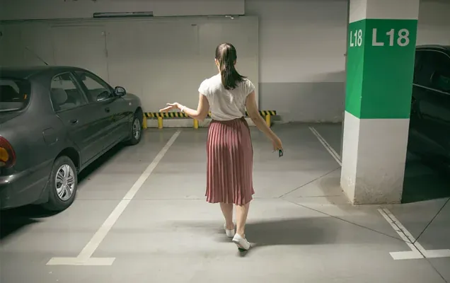Woman walking through an underground car park with her car key in hand