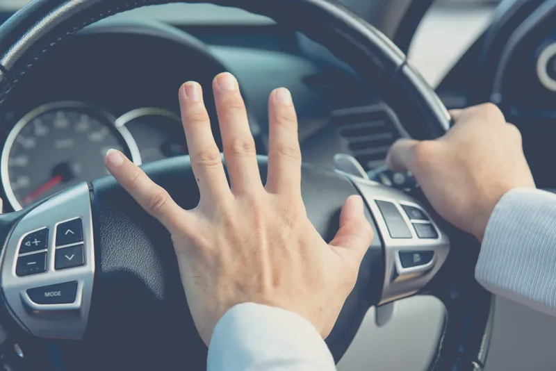 Driver pressing the horn in the centre of the steering wheel