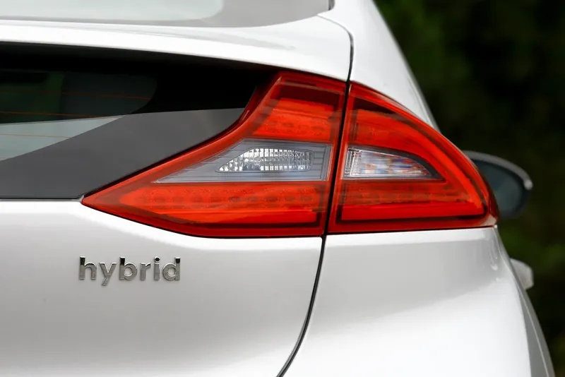 Hybrid badge beside the tail-light on the back of a white car