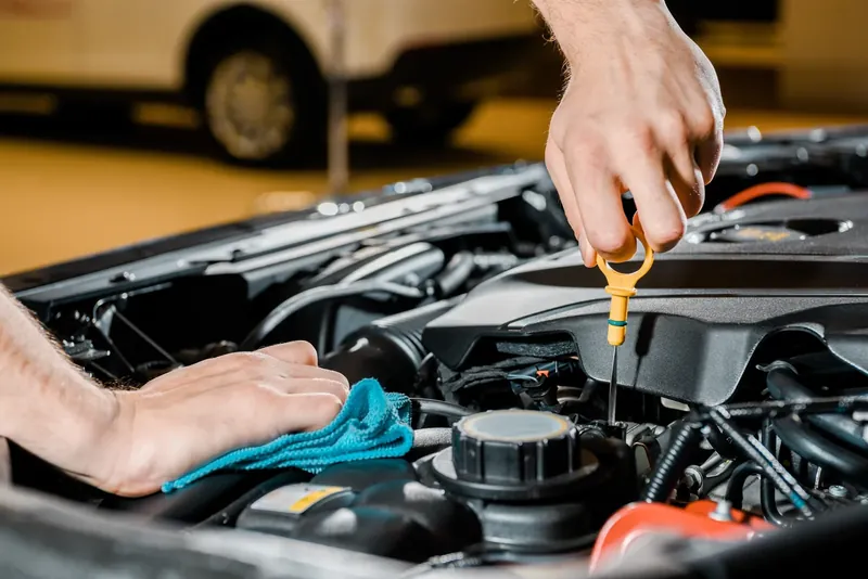 Mechanic checking the oil dipstick under an open bonnet
