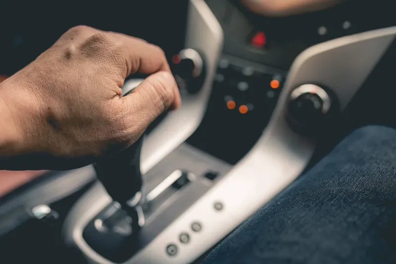 Hand resting on an automatic gear selector in a car's centre console