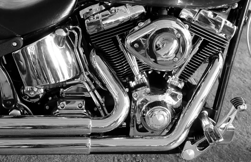 Black and white close-up of a chrome V-twin engine's cylinders and exhaust pipes
