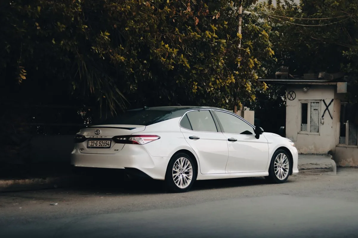 A white Toyota Camry sedan parked on a quiet street