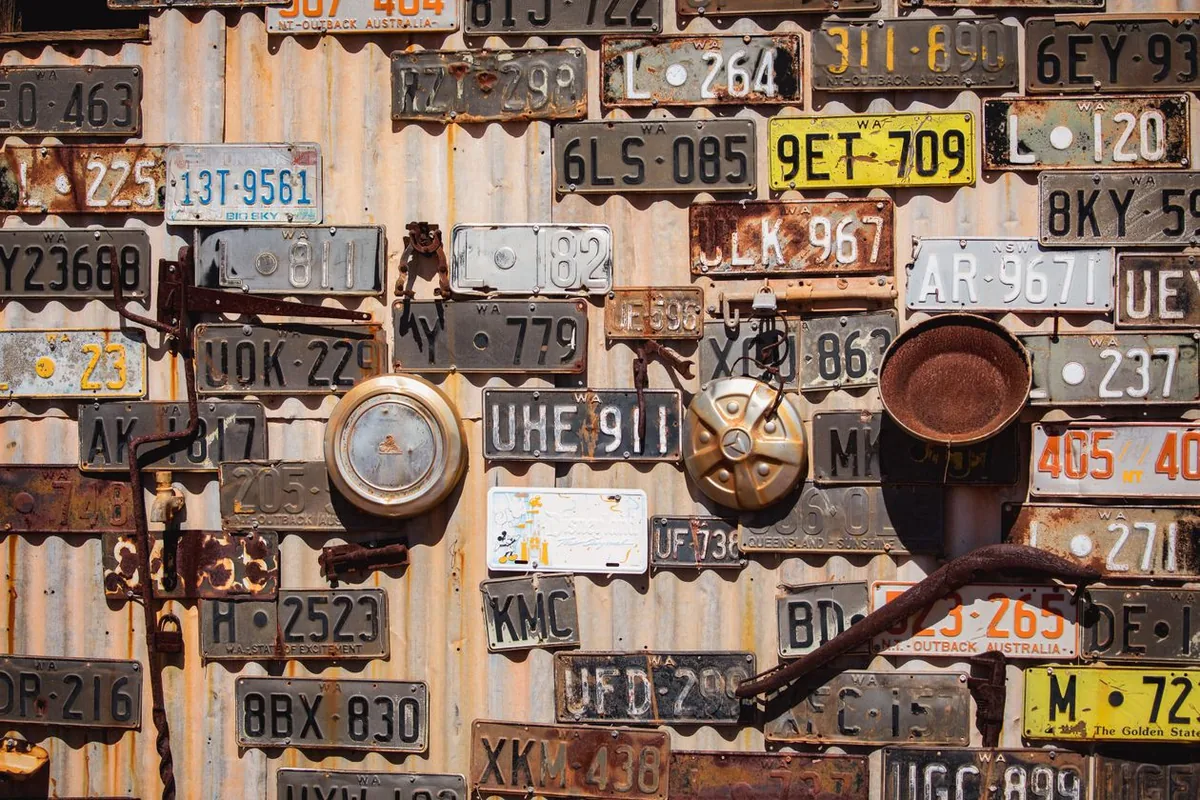 Old Australian number plates nailed to a corrugated iron wall in Leonora